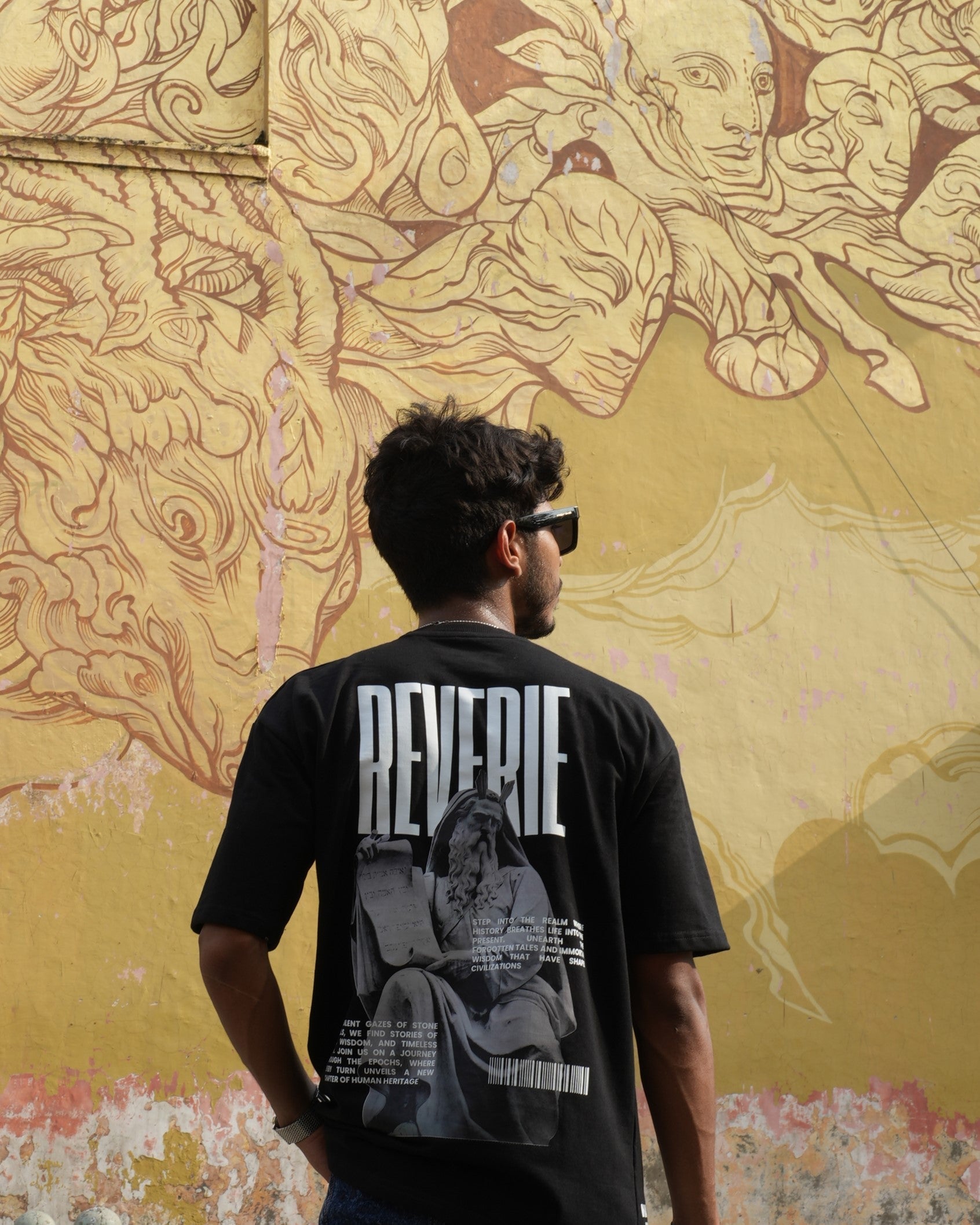Model showcasing a graphic tee from the best limited-edition streetwear brands against a vibrant mural backdrop