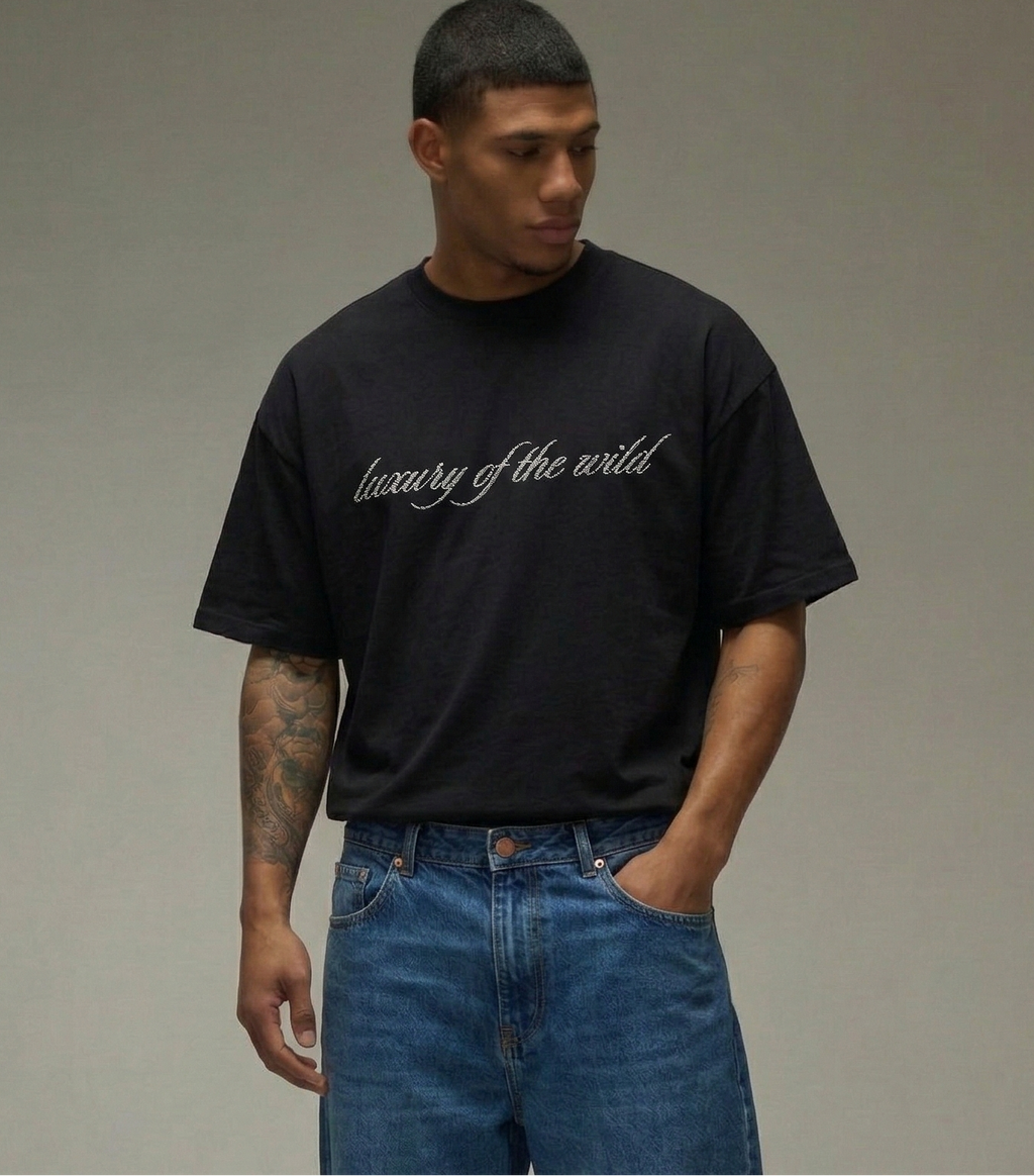 Man wearing a black t-shirt and blue jeans against a gray background