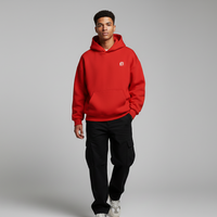 Person wearing a red hoodie with a small logo on a gray background