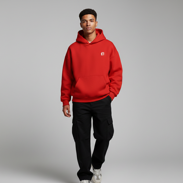 Person wearing a red hoodie with a small logo on a gray background