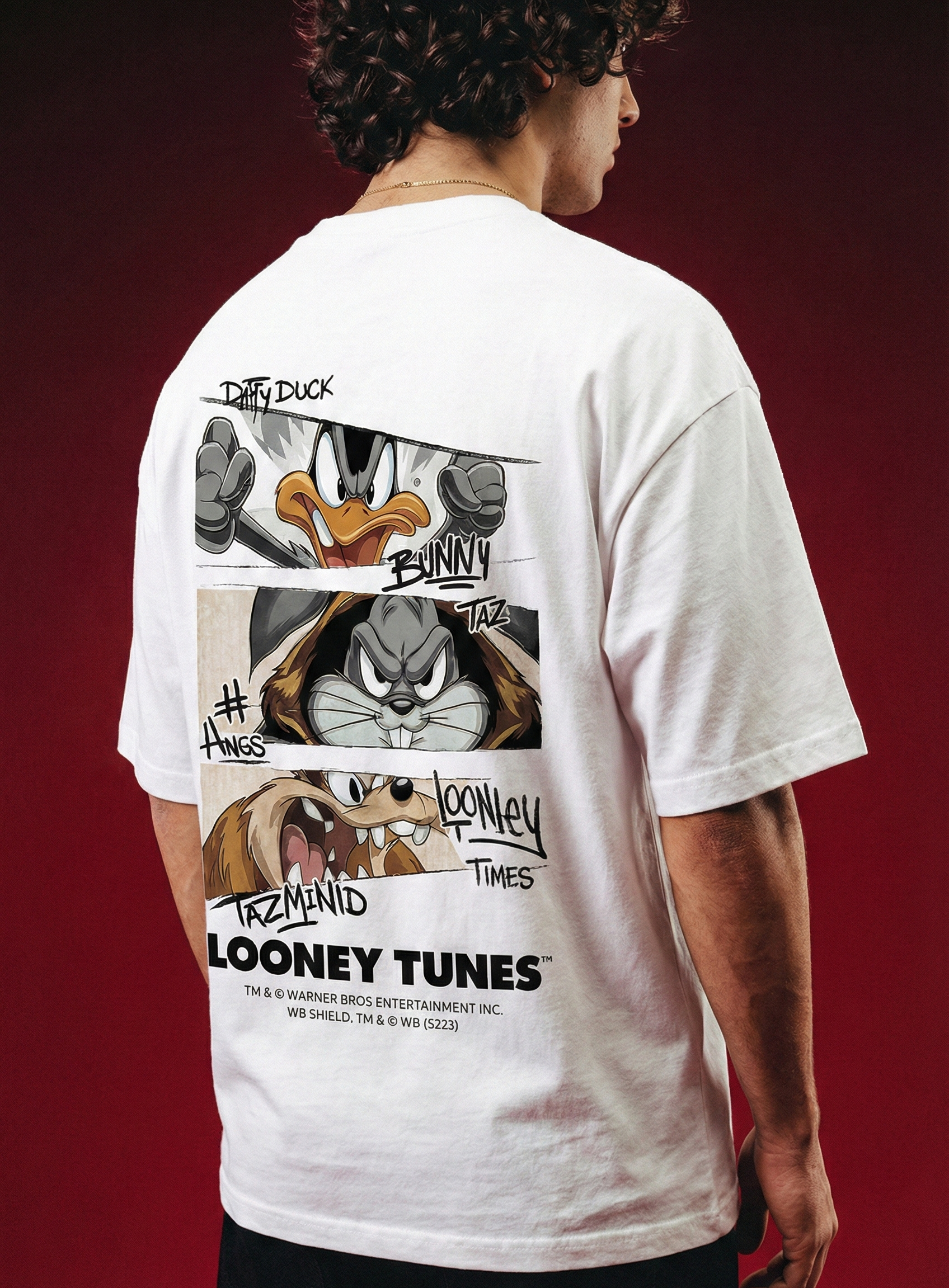 Person wearing a white t-shirt with Looney Tunes graphics on the back against a red background