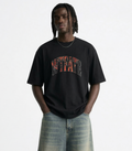 Person wearing a black t-shirt with colorful text and light blue jeans on a white background